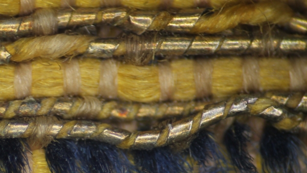 Detailní snímek sametové hedvábné tkaniny se zatkanými dracounovými nitěmi ze zlaceného stříbra. Zdroj: Národní muzeum